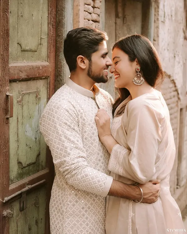 An intimate and happy moment shared between a couple in the rustic lanes of Old Delhi. The warm light and textures of the old door create a beautiful, romantic atmosphere.