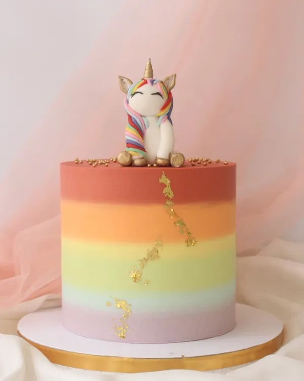 A vibrant rainbow gradient cake topped with a cute, sleepy unicorn. I added a touch of edible gold leaf for a little bit of magic.
