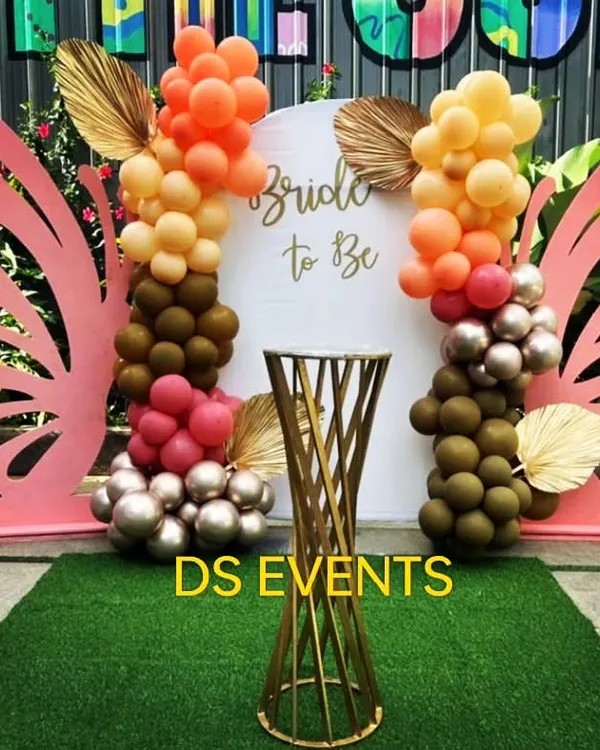 A whimsical 'Bride to Be' backdrop for a bridal shower. This design features large pink butterfly wings, a custom sign, and an organic balloon garland in a trendy color palette of orange, brown, and blush.