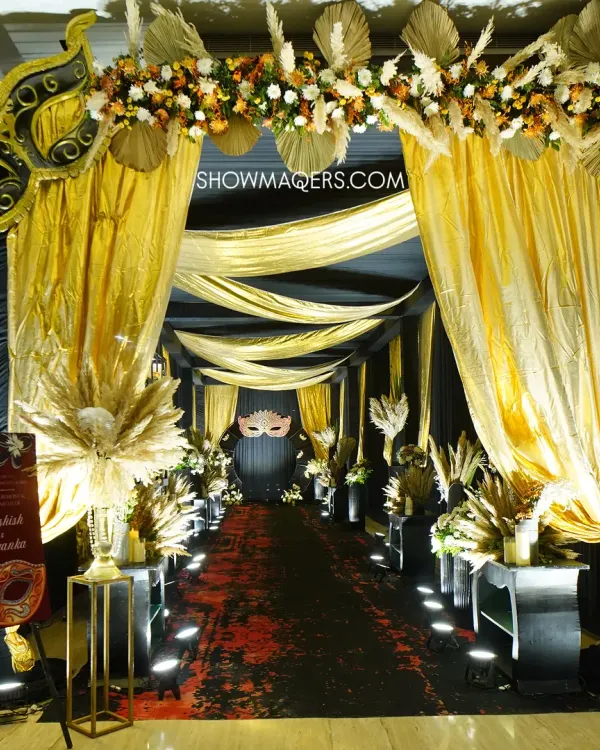 A dramatic and glamorous entrance for a black and gold masquerade themed Sangeet. We used shimmering gold drapes, pampas grass arrangements, and theatrical lighting to create a grand sense of arrival.