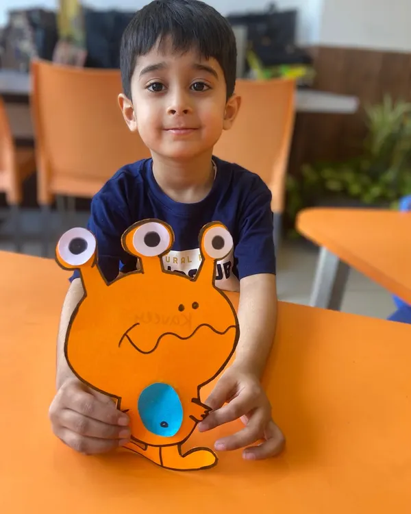 A student proudly holds up the colorful alien he made. Our craft sessions let children bring their wildest ideas to life while practicing fine motor skills.