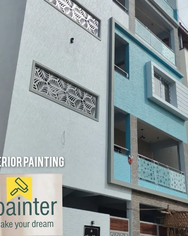 A modern apartment building with a fresh exterior paint job in light blue and white. A professional finish like this significantly boosts a property's curb appeal.