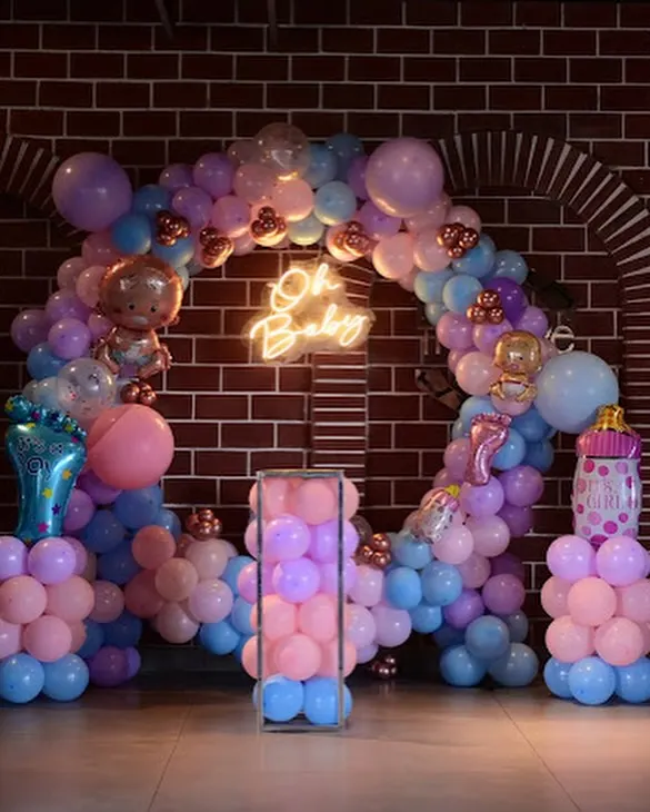 An "Oh Baby" themed baby shower setup. The circular balloon arch with a neon sign creates a perfect photo backdrop. We included baby-themed foil balloons like bottles and footprints for a playful touch.