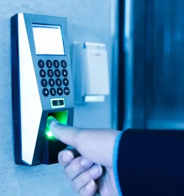 A close-up of a user authenticating with a wall-mounted biometric fingerprint scanner. We install these advanced access control systems to provide secure, keyless entry for commercial buildings and offices, ensuring only authorized personnel can access restricted areas.