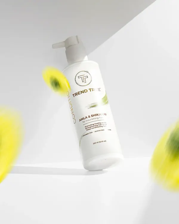 A creative shot of a Trend Tree conditioner bottle, seemingly floating with blurred elements suggesting motion and natural ingredients. This dynamic style is great for capturing attention on social media.