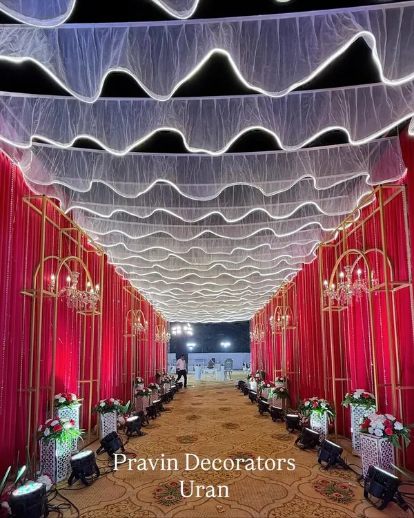 I love creating a grand entrance that makes your guests feel like they're stepping into another world. This walkway uses dramatic red draping, illuminated ceiling waves, and elegant chandeliers to build excitement from the very first step.