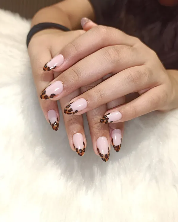 A classic French with a wild twist. This design features a traditional nude base on almond-shaped nails, but the tips are finished with a hand-painted leopard print for a fun and fierce look.