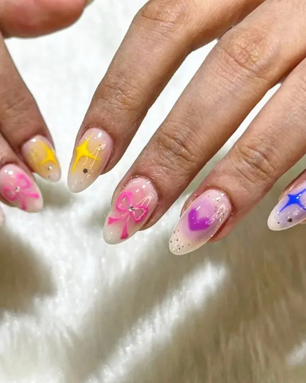 A close-up of the watercolor floral nails, showing the delicate, blended colors and the cute bow and star details that add a playful touch.