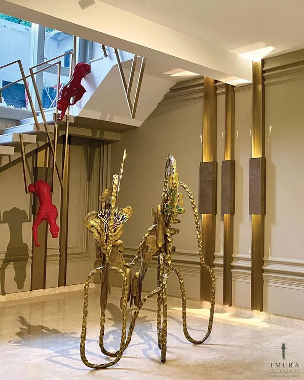 An entryway should be an experience. We used a combination of bold color and luxurious materials, with striking red panther sculptures climbing the custom brass staircase railing and a unique golden console table.