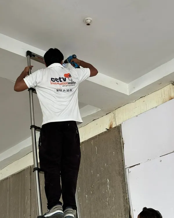 A technician from my team carefully drills a mounting point for a ceiling dome camera. We ensure every installation is precise and secure.