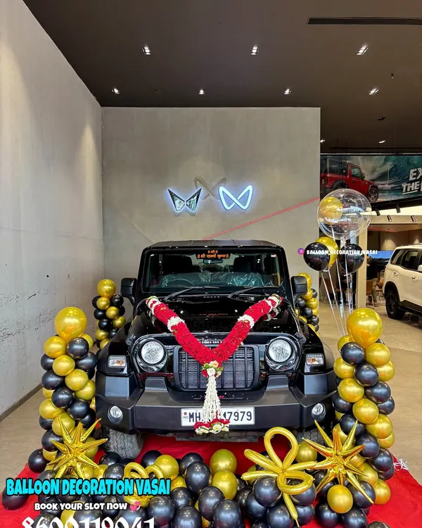 I created this stunning black and gold balloon setup for a new Mahindra Thar delivery. The display includes balloon pillars, star-shaped foil balloons, and a traditional red and white flower garland to make the vehicle handover ceremony truly memorable.