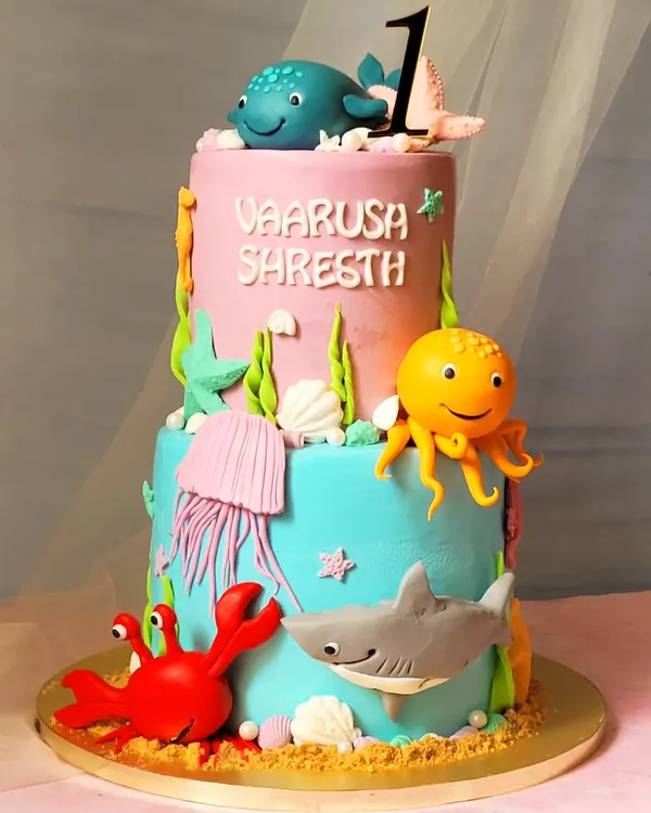 A vibrant two-tier "Under the Sea" themed cake. This one features a friendly shark, octopus, crab, and whale, all handcrafted to create a fun underwater adventure.