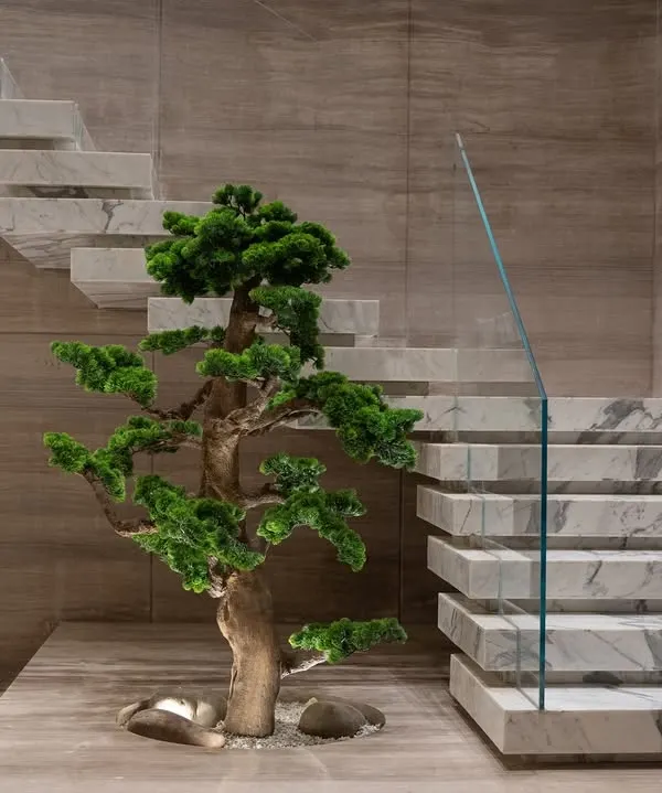 This stunning faux bonsai, set against minimalist marble and wood, exemplifies sculptural elegance. It's a perfect example of how a single plant can become a piece of living art in a modern home.