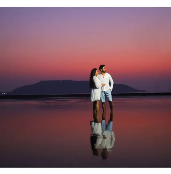 A silhouette of a couple against a stunning purple and pink sunset, their reflection captured perfectly in the still water below. This is the kind of magical, romantic pre-wedding photography I love to create.
