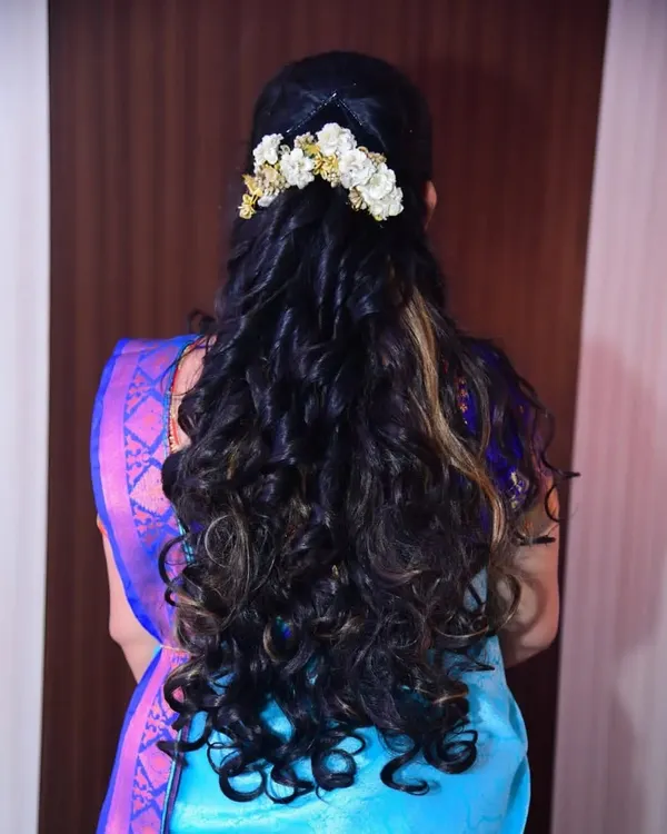 An example of a modern hairstyle with soft curls and a decorative flower accessory. This is a popular choice for receptions and parties.