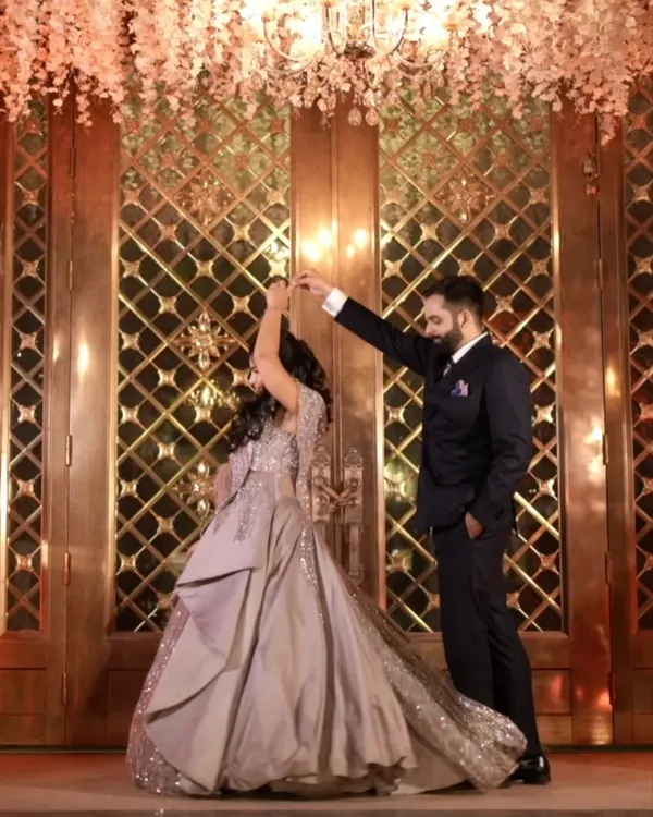 The first dance as an engaged couple. This beautiful shot captures the groom twirling his bride-to-be under a stunning floral chandelier, creating a fairytale moment.