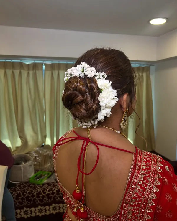 This is my signature classic bridal bun, intricately woven and adorned with fresh white flowers. It is a timeless and elegant choice that ensures you look perfect from every angle on your wedding day.
