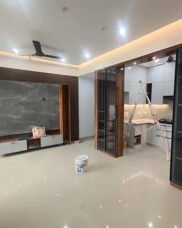A nearly completed living area, showing the integration of the TV unit and the open kitchen entrance. The design focuses on clean lines and a harmonious flow between spaces.