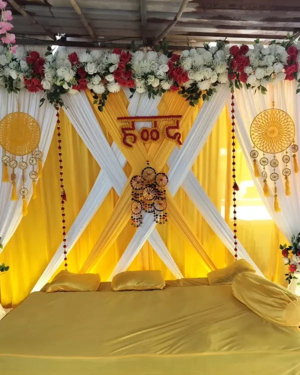 A traditional Haldi seating arrangement with bright yellow and white drapes. We've added bohemian-style dreamcatchers and floral arrangements to create a festive look.