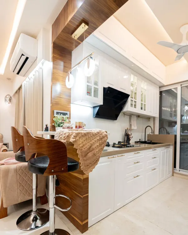 This beautiful all-white kitchen features classic shaker-style cabinets and is perfectly integrated with a wooden breakfast bar, creating a warm and inviting open-plan space.