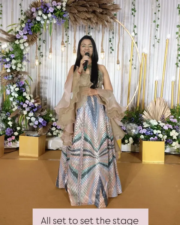 All set to take the stage and kick off a beautiful engagement ceremony. With a stunning backdrop and a mic in hand, I'm ready to weave together moments of tradition, love, and celebration.
