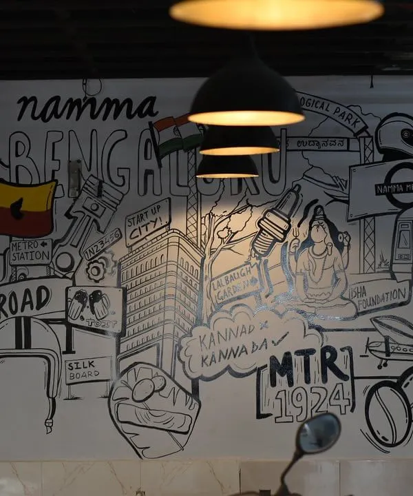 We brought the spirit of our city to life with this 'Namma Bengaluru' doodle mural for a local cafe. This black and white line art collage features iconic landmarks like the Vidhana Soudha, MTR, and Namma Metro, creating a vibrant and engaging wall that tells a story.