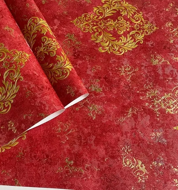 A stunning close-up of a bold red wallpaper with a traditional gold damask pattern, showing its rich color and texture.