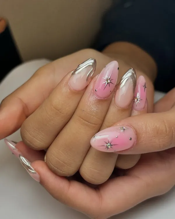 This look is out of this world. It combines a soft pink ombre base with bold silver chrome details and sparkling star-shaped gems for a truly celestial vibe.