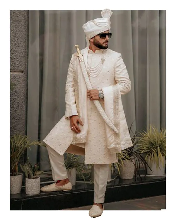 A portrait of pure regality. We designed this custom ivory sherwani for the groom who desires a look of classic, understated majesty on his wedding day, complete with a traditional turban and sword.