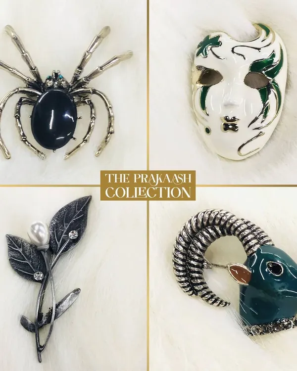 A showcase of our diverse brooch collection. This set includes a silver-tone spider with a black stone, an abstract enamel mask, a delicate leaf pin with a pearl, and a sculpted ram's head, highlighting our unique designs.