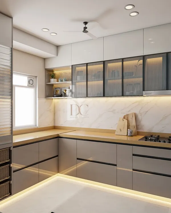 This L-shaped modular kitchen is designed for maximum efficiency. We used high-gloss grey laminate for the cabinets, a marble-finish backsplash, and fluted glass shutters on the upper cabinets for a modern, high-end look.