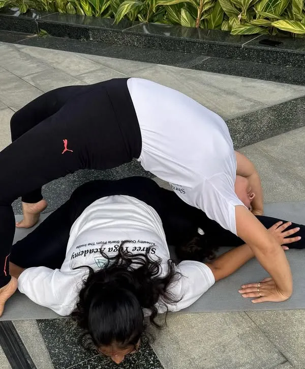Finding balance together. This partner pose combines a full split (Hanumanasana) with a deep wheel pose (Chakrasana), showcasing the strength and flexibility that comes from consistent practice and mutual support.