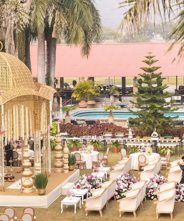 An overview of a stunning lakeside wedding setup at Shikarbadi Hotel, Udaipur. The golden, dome-shaped mandap is the focal point, surrounded by elegant guest seating, creating a picturesque and regal ceremony space.