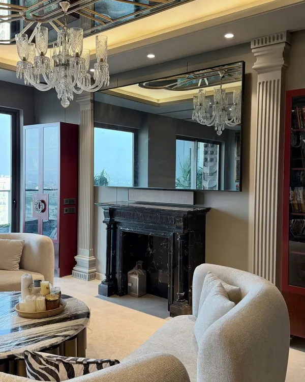 A luxurious living room at Gulshan Dynasty, Noida, featuring our custom-made boucle sofas, a classic black marble fireplace, and a striking red display cabinet. The design blends modern comfort with timeless, classical elements.