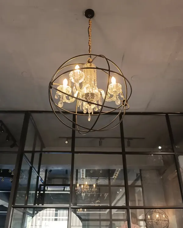 For this dance and fashion studio, we used an industrial-chic aesthetic with exposed ceilings and glass partitions. The statement chandelier, a crystal fixture within a metal orb, adds a touch of glamour to the space.