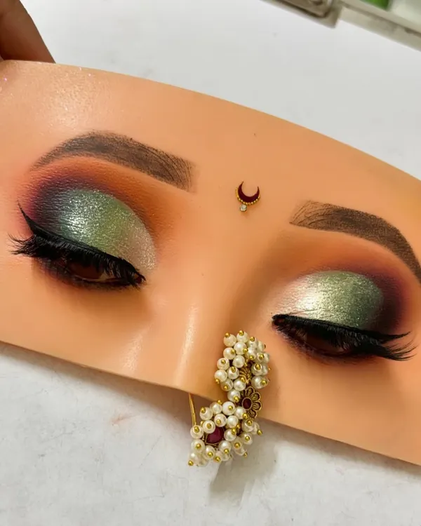 A dramatic green and silver half-cut crease eyeshadow look. This was created on a practice mannequin to perfect the blending and shimmer application.