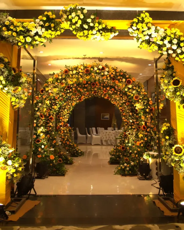 A magnificent entrance for a Haldi ceremony, featuring a grand archway completely covered in vibrant sunflowers and yellow blooms, creating an immersive floral experience.