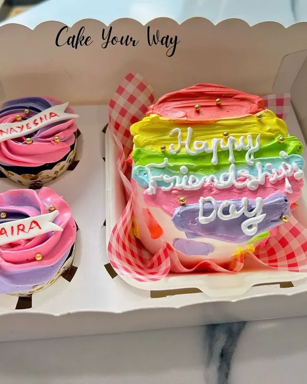 A colorful bento box for Friendship Day. This set includes a mini rainbow cake and two personalized cupcakes, making it a sweet and thoughtful gift for your best friends.