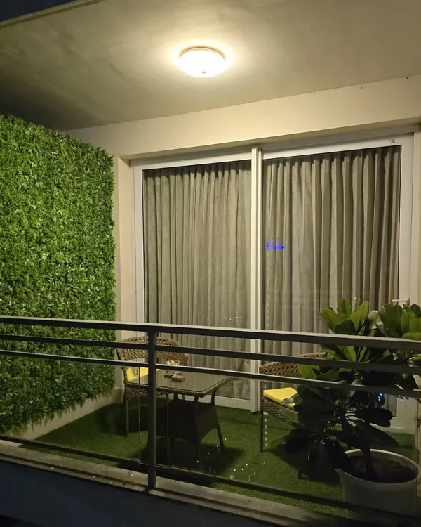 The perfect small balcony makeover. A lush artificial grass floor and a dense green wall turn this into a private, positive space.