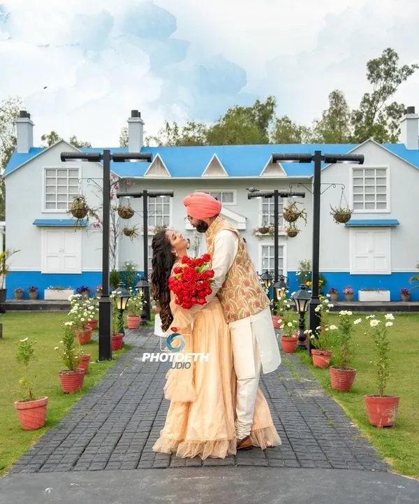 A beautiful, wide-angle shot of a couple at a picturesque location. The grand house and manicured garden provide a perfect backdrop for a classic and romantic pre-wedding photo.