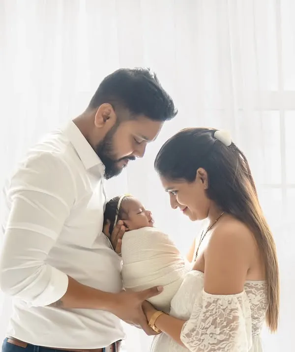 A beautiful, light-filled portrait of new parents cherishing their newborn. This classic high-key style, shot against our studio's window light, creates a timeless and angelic feel, focusing purely on the connection and love in the first few days of a new family.
