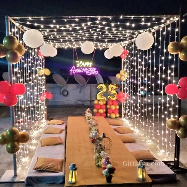A beautiful 25th anniversary celebration on a terrace. I set up a low-seating dining arrangement for a group, enclosed in a frame decorated with fairy lights, balloons, and paper lanterns.