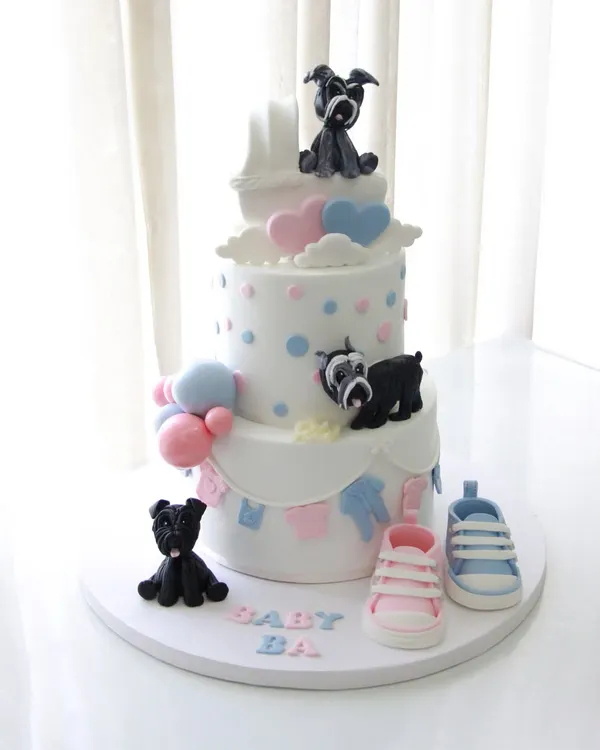 A dreamy three-tiered baby shower cake for a client whose journey I've been a part of from their engagement to their wedding. This cake features pink and blue details, tiny baby shoes, and adorable fondant schnauzer dogs to include their fur babies in the celebration.