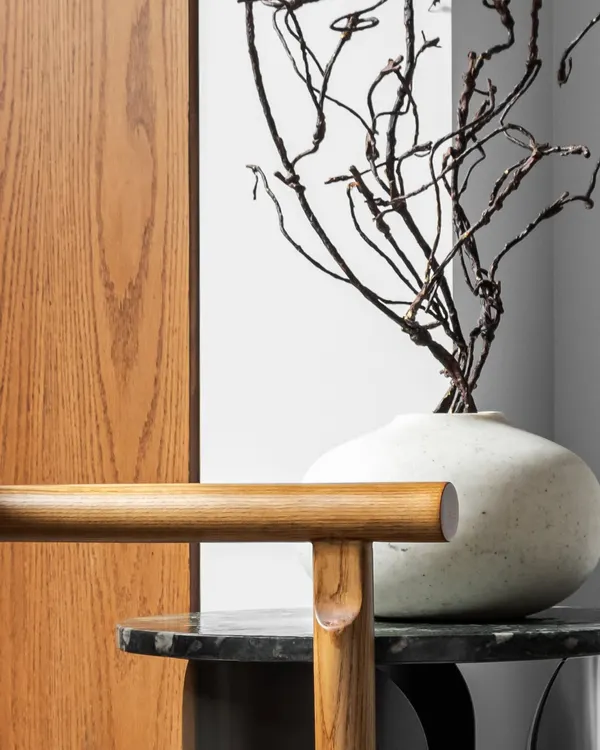 There is a timelessness in the pairing of raw stone and natural wood. This composition of a dark marble side table, a warm wood chair, and sculptural dried branches explores the balance of strength and warmth, texture and tone.