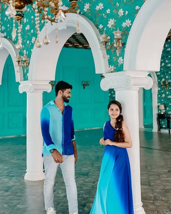 A candid moment in a beautiful palace setting. The ombre blue gown complements the man's coordinated shirt, creating a stylish and modern look for this couple's photoshoot.