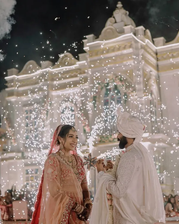 We love capturing the grand scale of your celebration. This stunning varmala moment, set against a beautifully lit palace facade with a brilliant display of cold pyro fireworks, highlights our expertise in filming large, destination weddings and turning them into spectacular cinematic events.