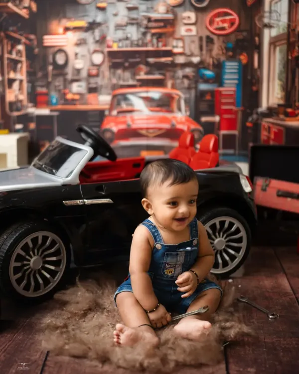 The happiest little mechanic in his own garage. This detailed setup, complete with a mini car and tools, is perfect for a fun and unique sitter session.
