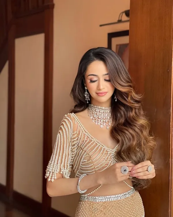 A glamorous look perfect for a reception or sangeet. I created these voluminous, side-swept Hollywood waves to complement the intricate pearl and diamond jewelry, ensuring the hair feels as luxurious as the outfit.