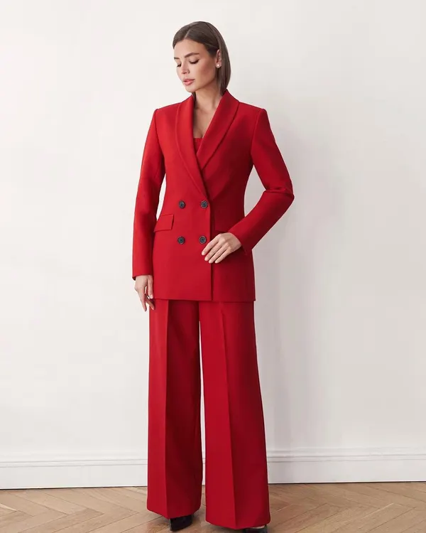This custom-tailored, double-breasted power suit in a striking red is the definition of confidence. The wide-leg trousers and sharp blazer are crafted from premium crepe fabric for a flawless drape and comfortable fit.