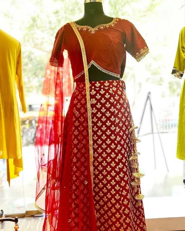 This custom-designed red lehenga is crafted from rich brocade fabric with delicate buti patterns. It's paired with a simple, elegant blouse and a lightweight net dupatta, creating a balanced and timeless bridal look.